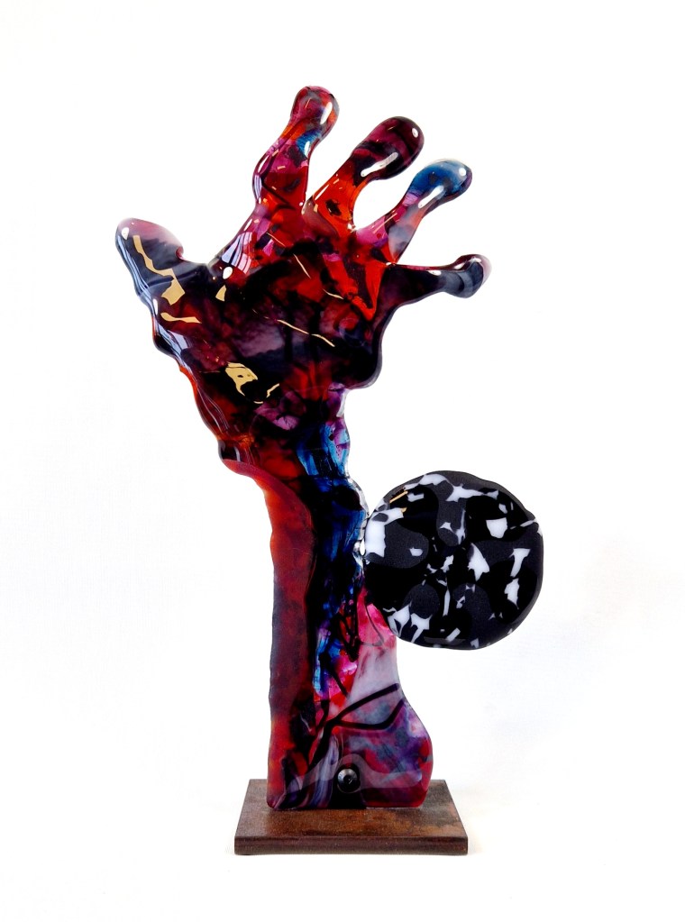 Full frontal view of the glass sculpture Second Signal, showing an upward-reaching hand mounted on an iron base.